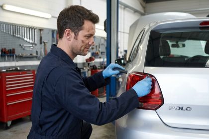 Mécanicien retirant le feu arrière d'une Volkswagen Polo 5 dans un atelier automobile